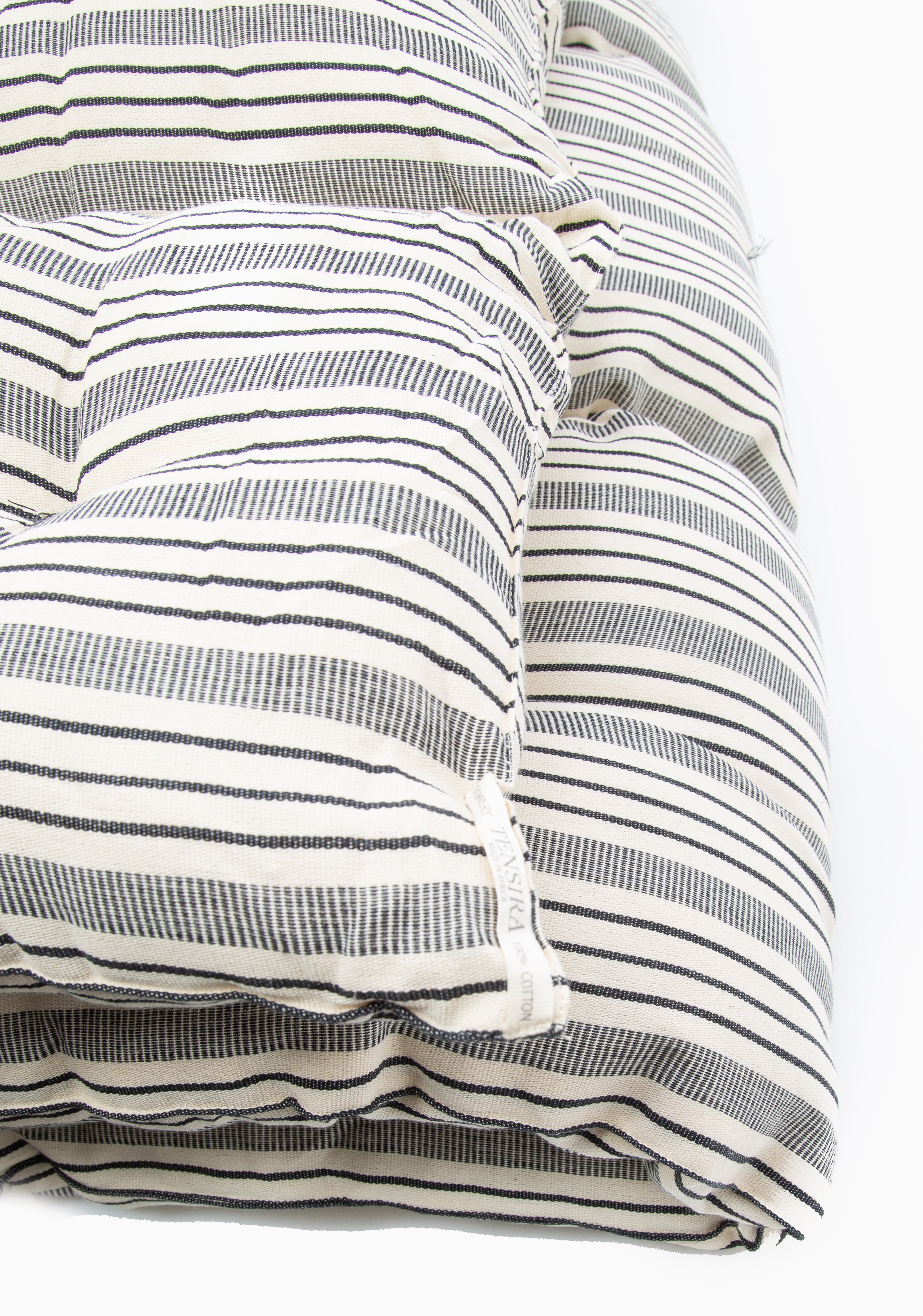 Artisan-made bed roll with natural color palette and striped design, perfect for picnics, beach days, or backyard naps.