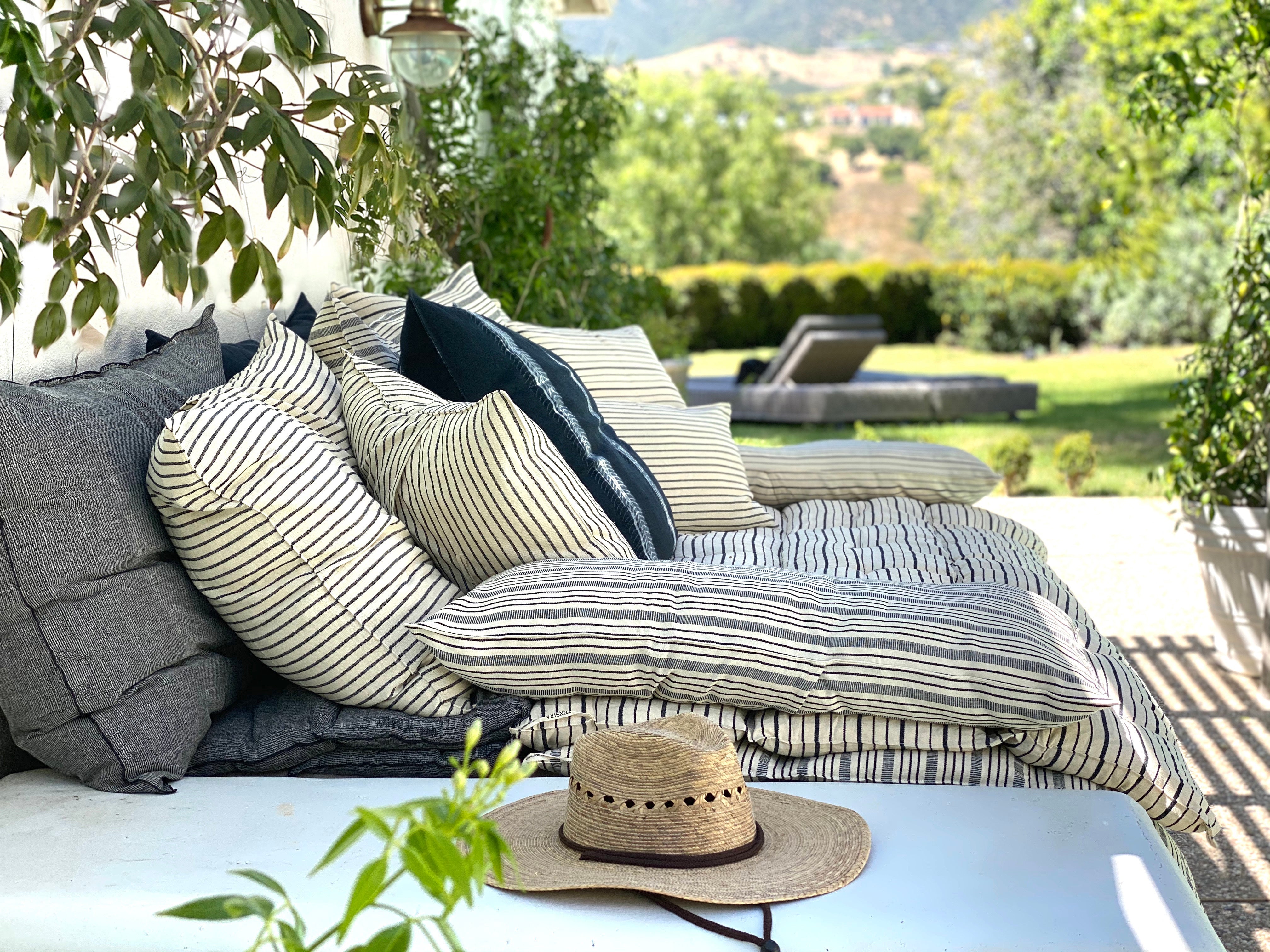 Striped cotton bed roll from the DIANI x Tensira collection, ideal for relaxed garden picnics and sustainable outdoor living.