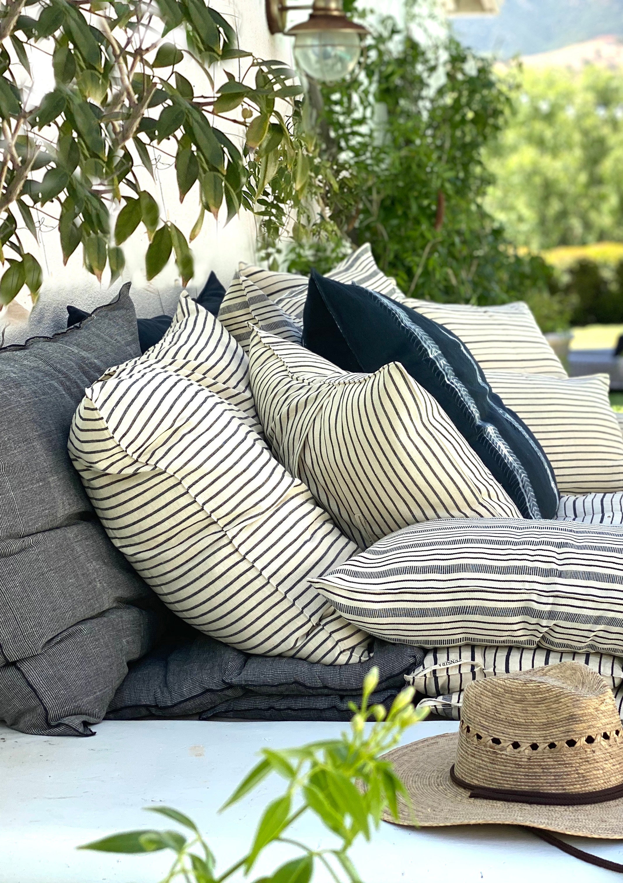 Eco-conscious long cushions in a mix of solid and striped patterns, featuring hand-dyed yarns and artisan-made cotton fabric from Guinea. Perfect for a quick afternoon nap or picnic in the garden. Available at Diani Boutique.