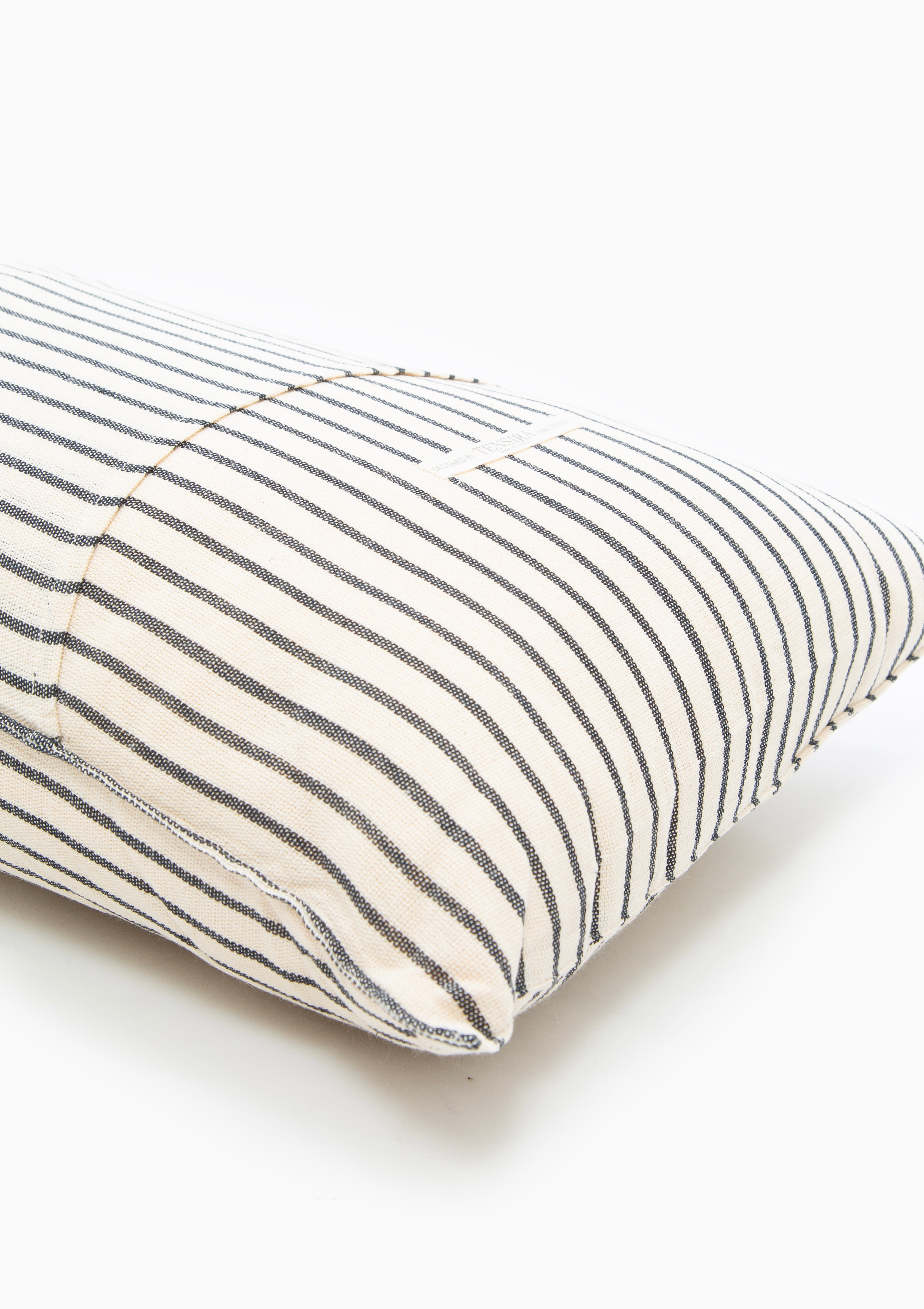Tensira x DIANI long cushions with bold stripes and earthy solids, showcasing traditional West African textile craftsmanship.
