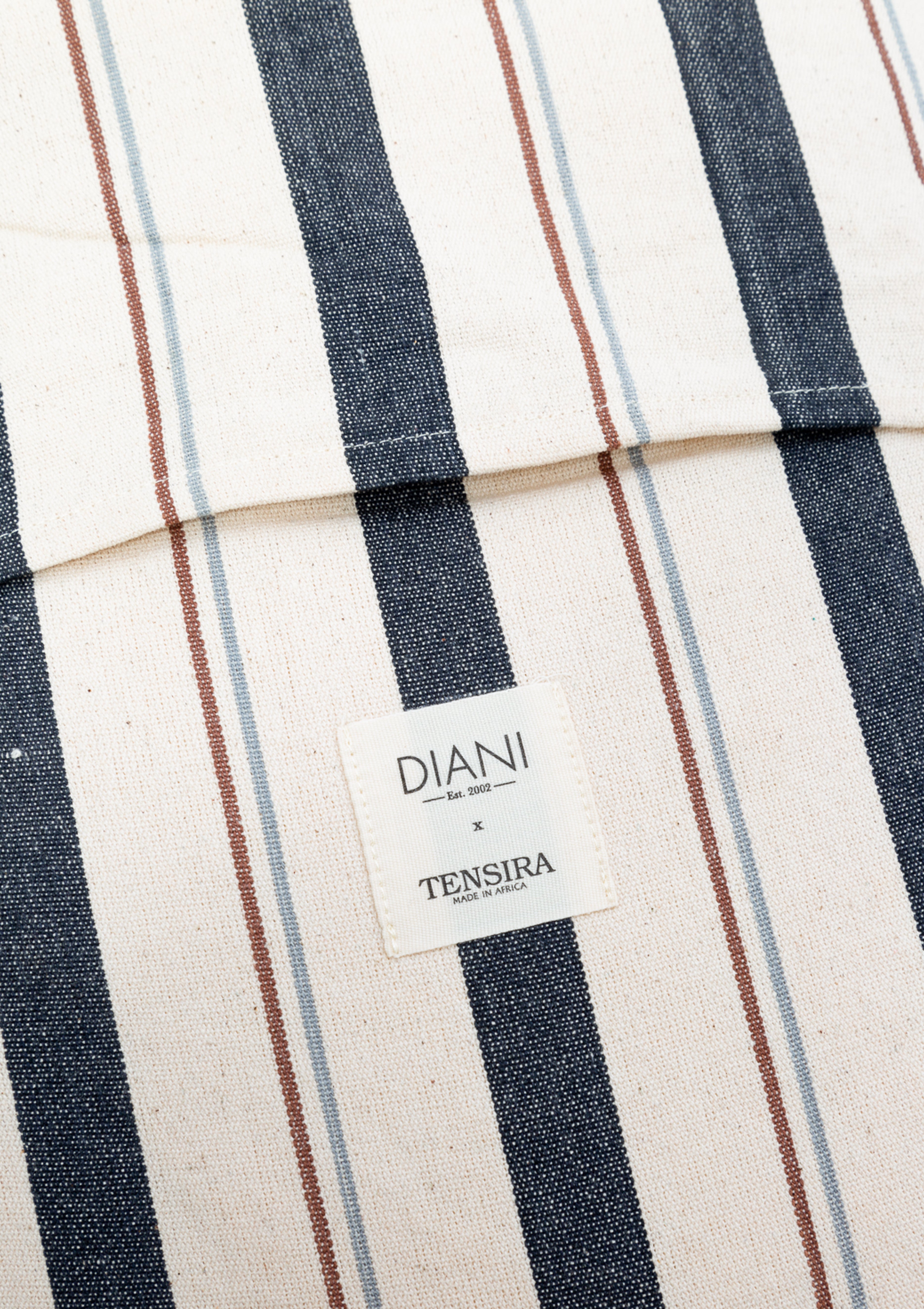 Eco-conscious long cushions in a mix of solid and striped patterns, featuring hand-dyed yarns and artisan-made cotton fabric from Guinea. Perfect for a quick afternoon nap or picnic in the garden. Available at Diani Boutique.