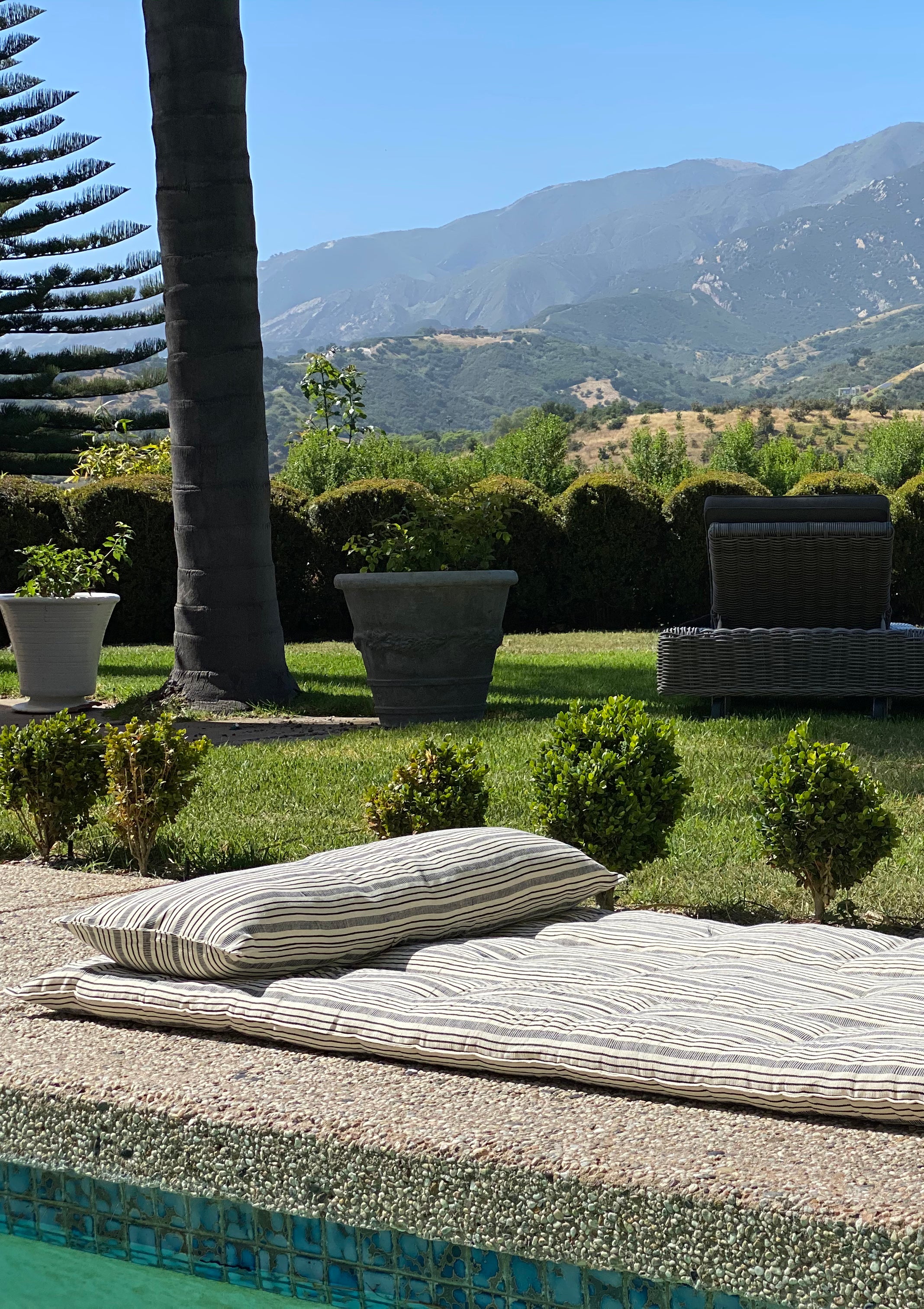 Tensira x DIANI long cushions with bold stripes, showcasing traditional West African textile craftsmanship. Perfect for that mid afternoon nap by the pool.