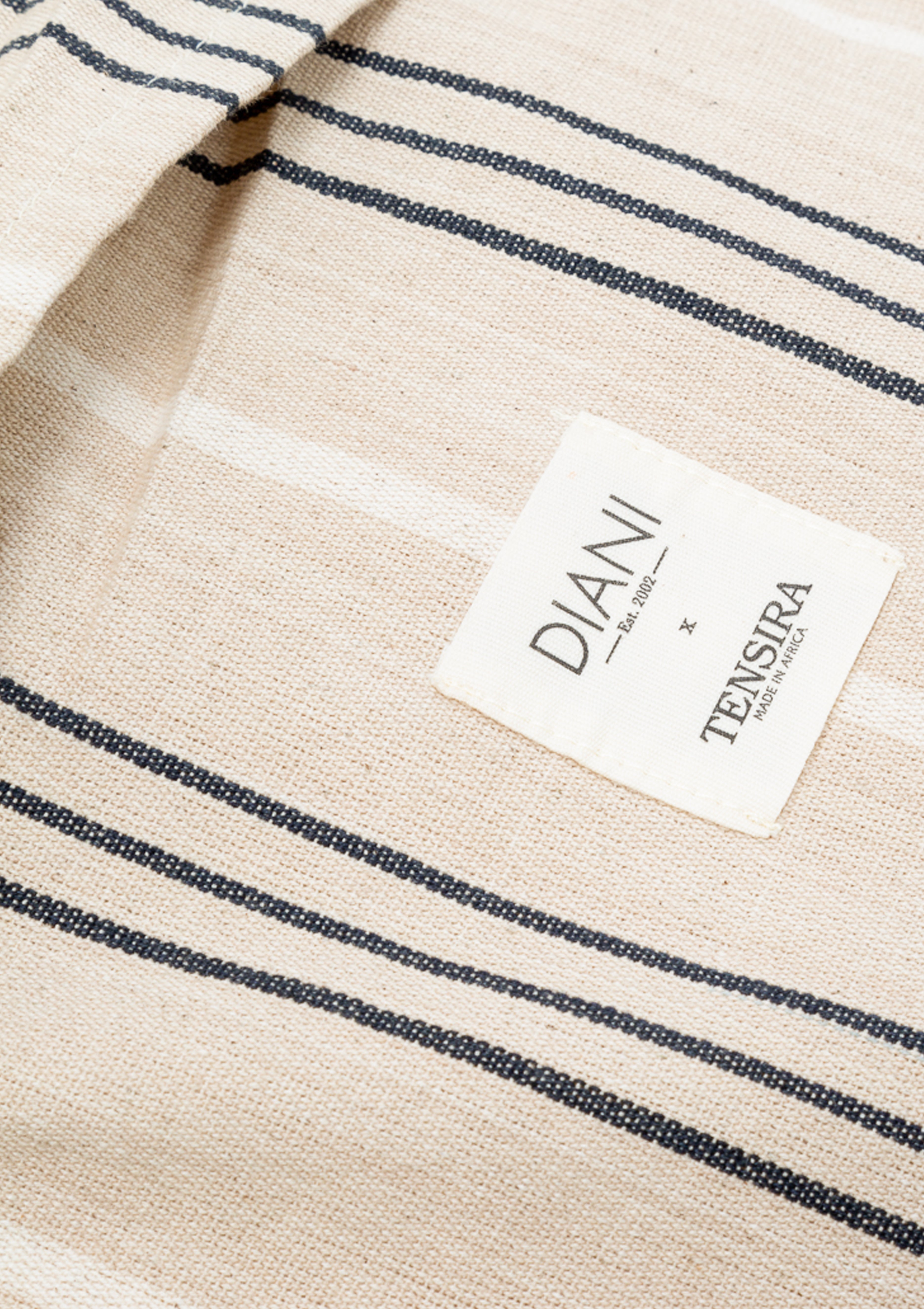 Long bolster pillow featuring a hand-dyed striped pattern, made from artisan-crafted cotton in a 14" x 48" size. May be used indoors or outdoors and available exclusively at Diani Boutique.