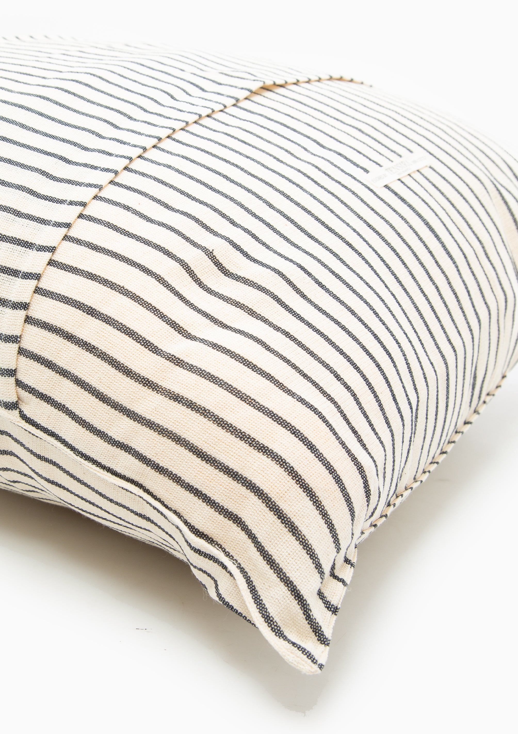 Close up of our striped cotton headboard cushion from Tensira, sustainably made in Guinea by artisan groups using zero-waste practices.