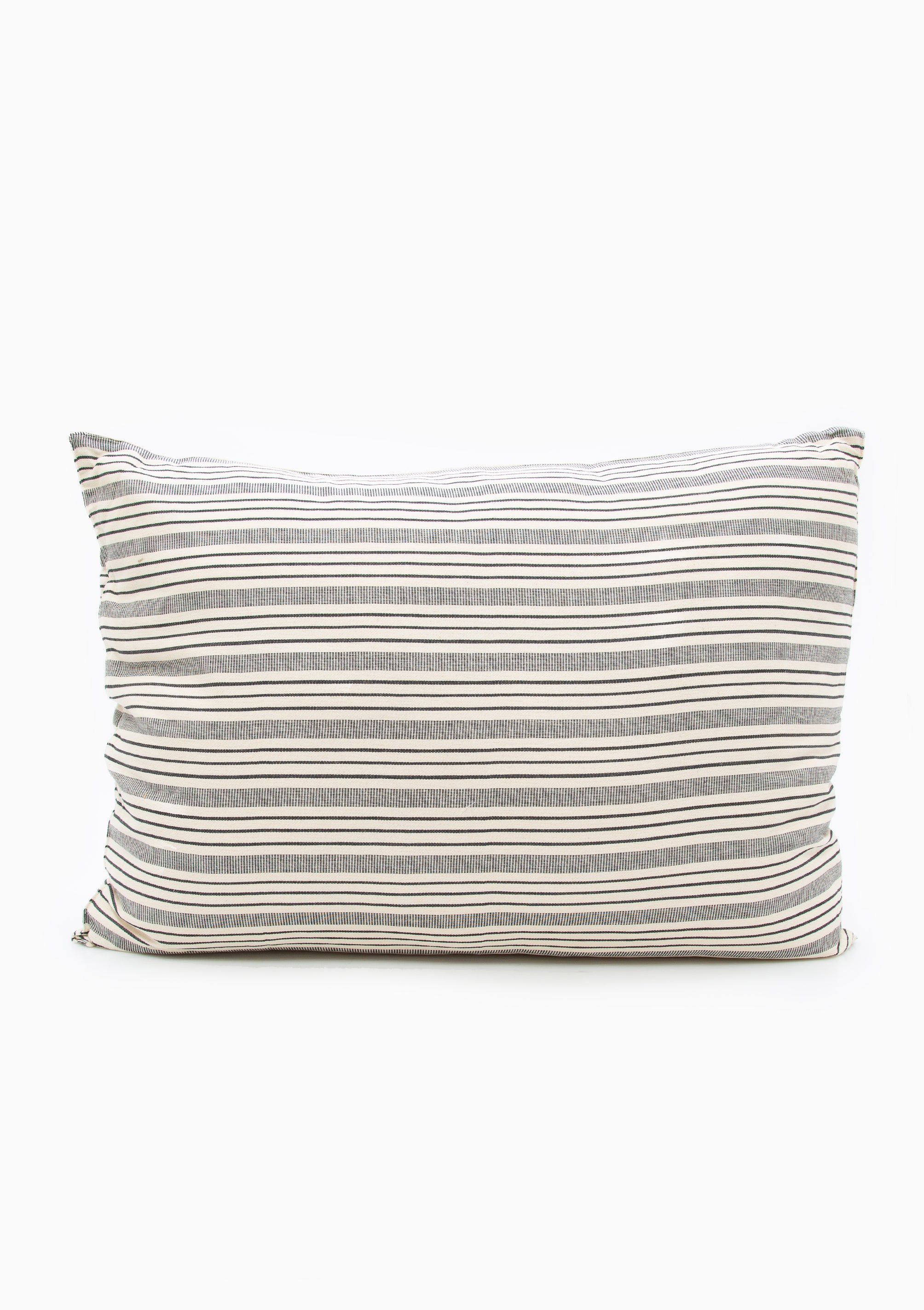 Tensira headboard cushion in soft, natural tones, featuring hand-dyed yarns and traditional weaving techniques.