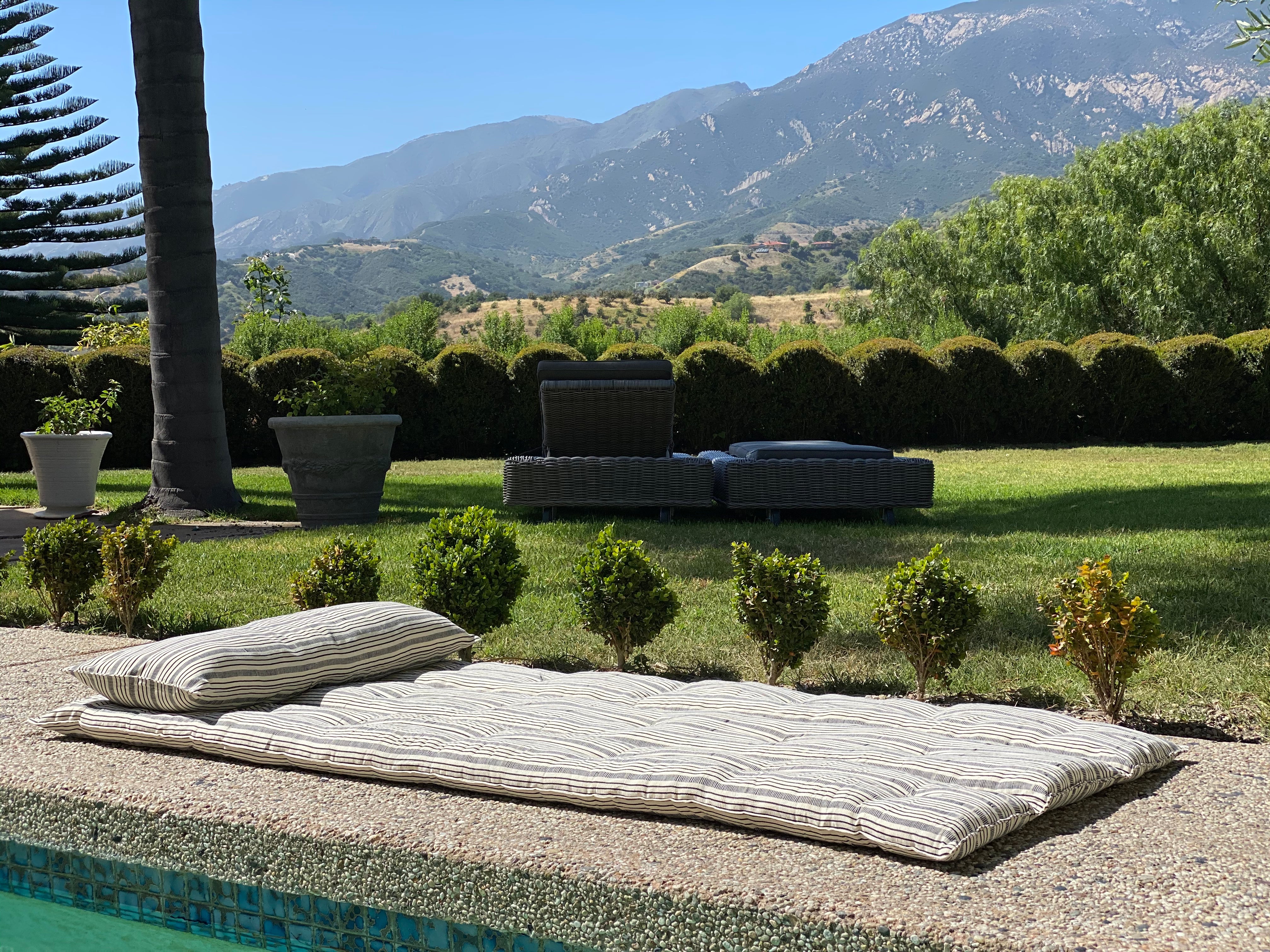 Striped and solid cotton cushions designed for lounging, handcrafted by artisan groups in Guinea for the Tensira x DIANI collection.