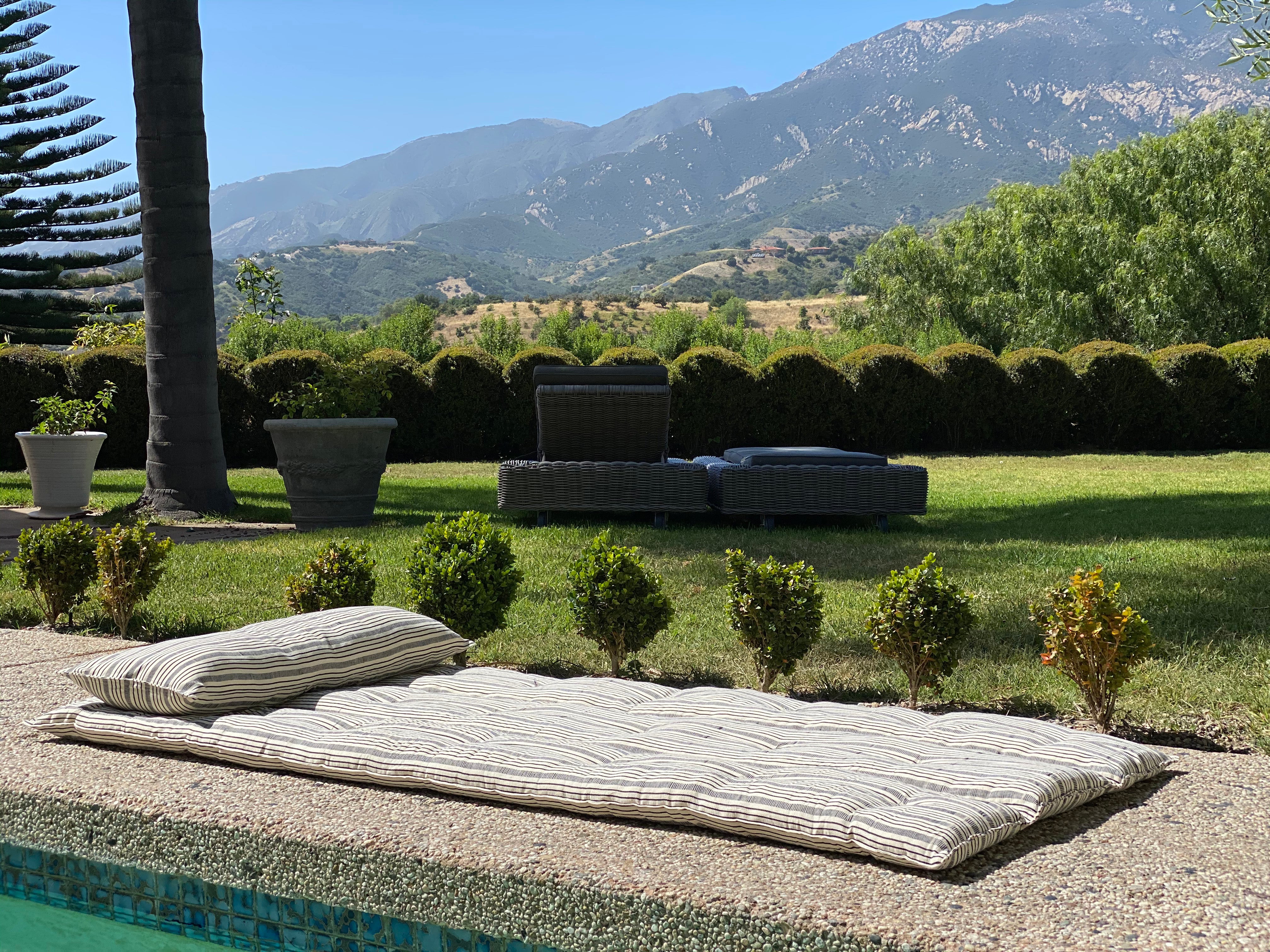 Artisan-made bed roll with natural color palette and striped design, perfect for picnics, beach days, or backyard naps.