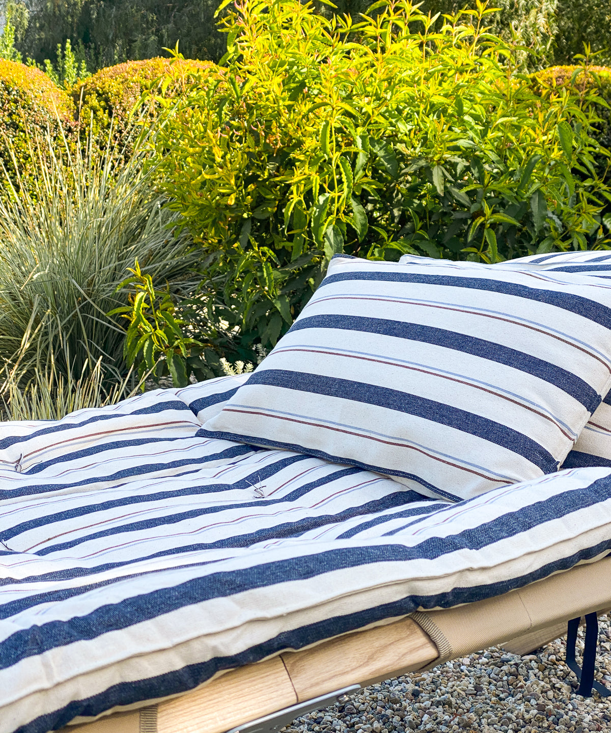 Striped cotton bed roll from the DIANI x Tensira collection, ideal for relaxed garden picnics, afternoon naps, and sustainable outdoor living.