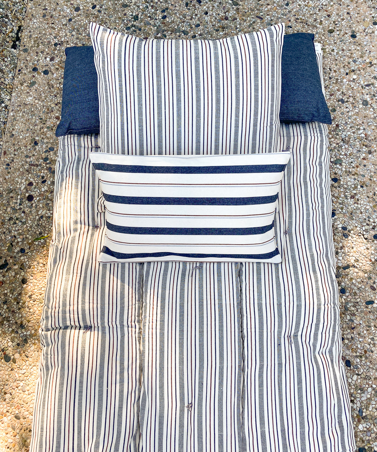 Eco-conscious long cushions in a mix of solid and striped patterns, featuring hand-dyed yarns and artisan-made cotton fabric from Guinea.