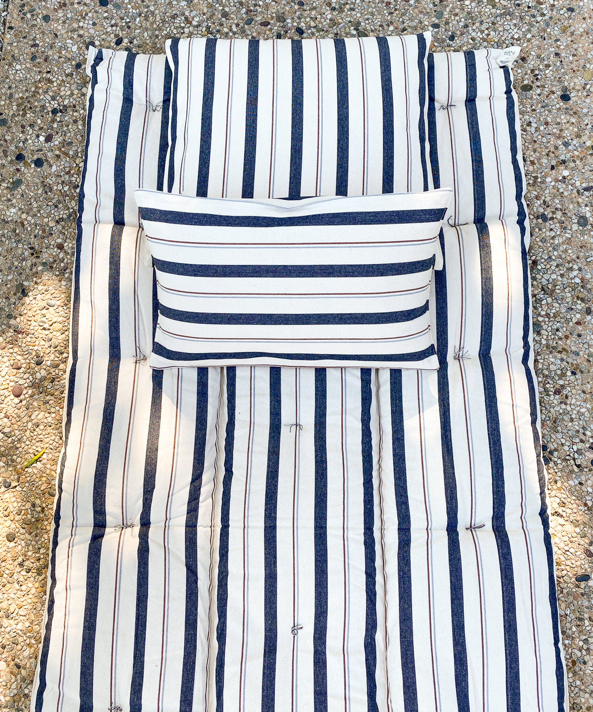 Striped cotton bed roll from the DIANI x Tensira collection, ideal for relaxed garden picnics, afternoon naps, and sustainable outdoor living.