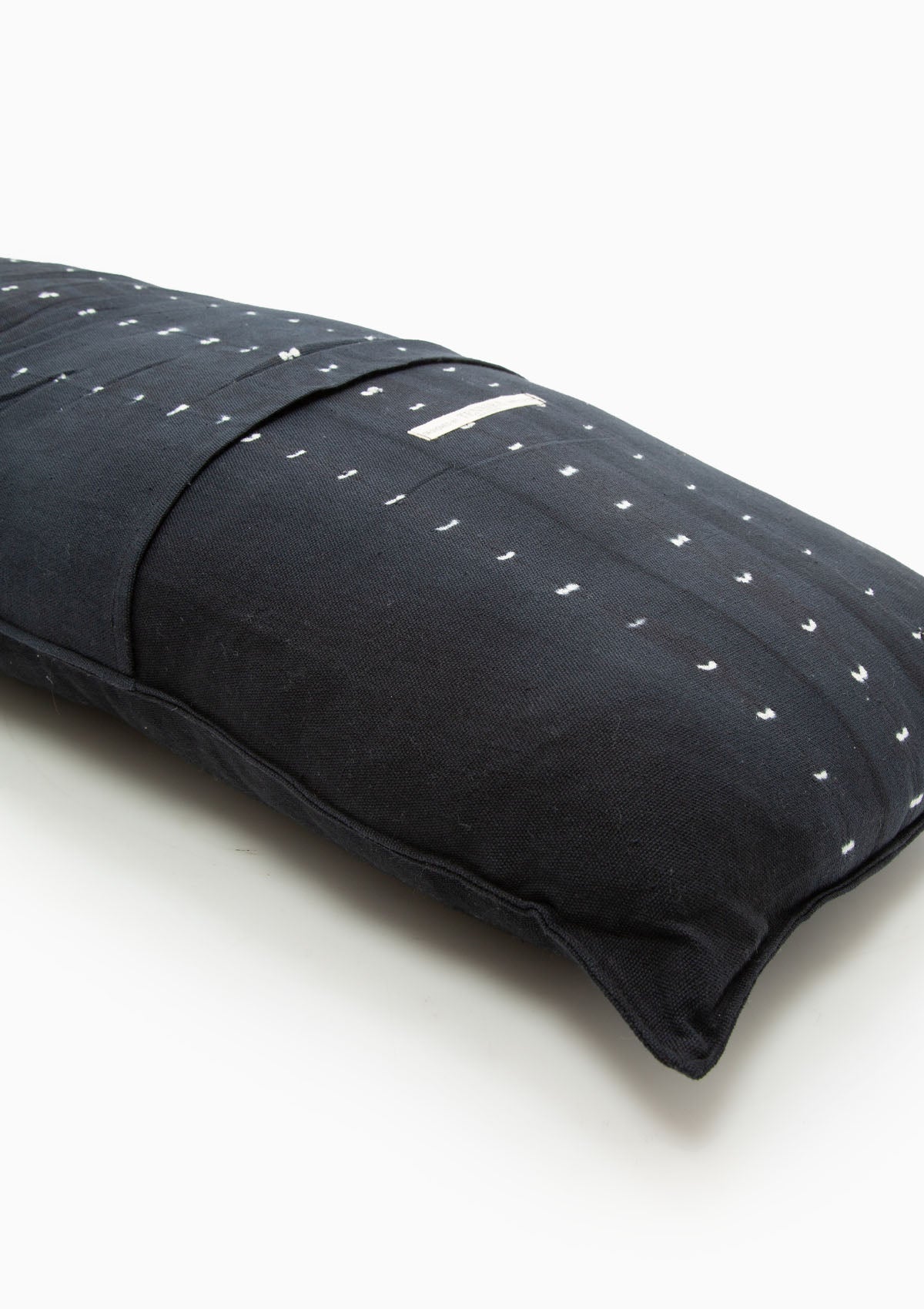 Navy dot batik bolster pillow in 14" x 48", crafted from hand-dyed cotton for a bold yet timeless accent.